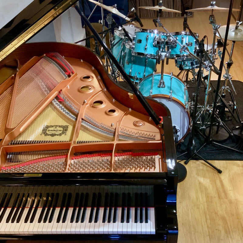 grand piano with lid open next to drum kit